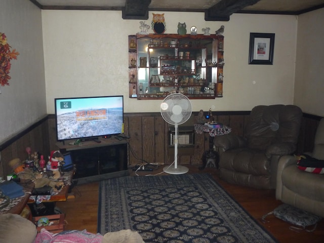 living room with wood-type flooring, beamed ceiling, wooden walls, and crown molding