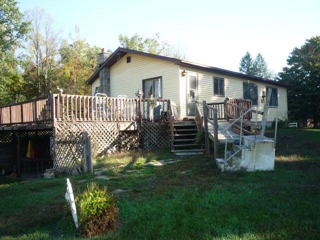 back of property with a wooden deck and a yard