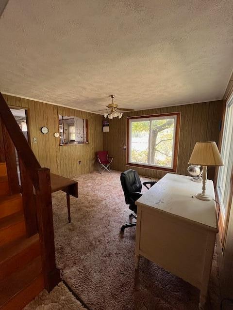 office area featuring wood walls, ceiling fan, dark carpet, and a textured ceiling