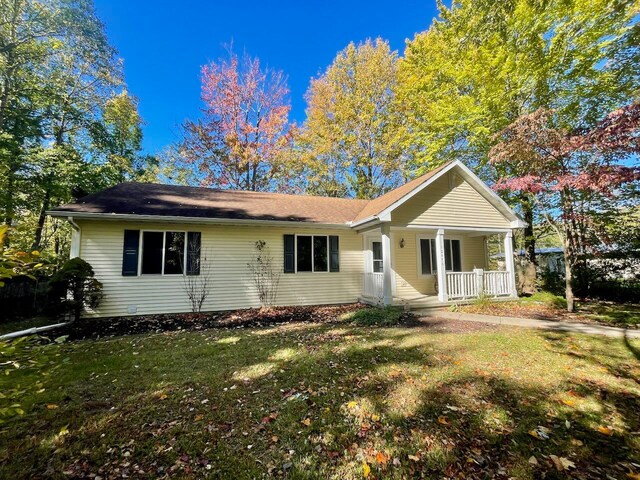 rear view of property with covered porch and a lawn