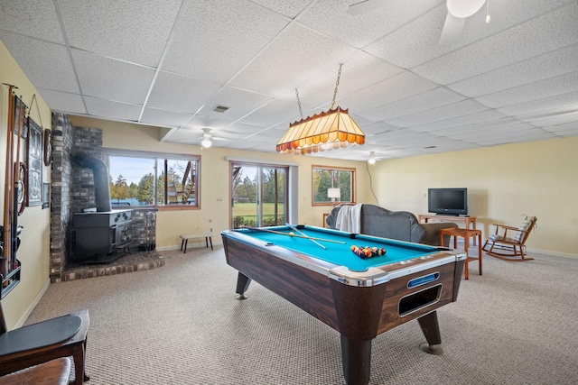 playroom with carpet floors, ceiling fan, billiards, a paneled ceiling, and a wood stove