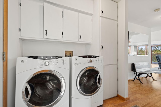 laundry area featuring cabinets, light hardwood / wood-style flooring, and washer and dryer