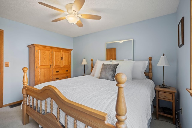 carpeted bedroom featuring ceiling fan and a textured ceiling