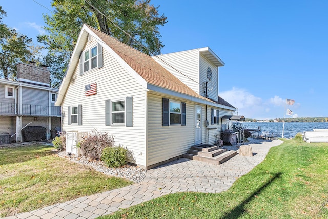 rear view of house featuring a water view, a yard, and a patio area