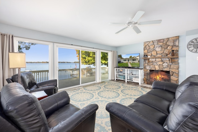 living room featuring a stone fireplace, hardwood / wood-style floors, and ceiling fan