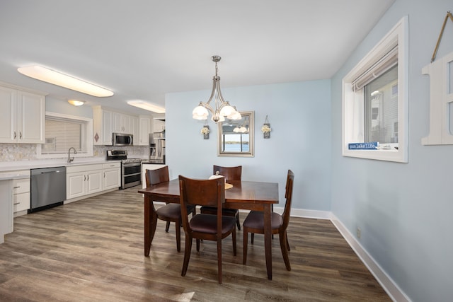 dining room with dark wood-type flooring, a notable chandelier, and sink