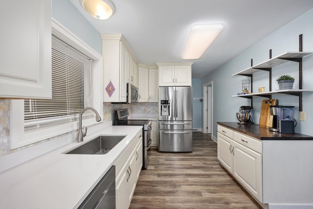 kitchen featuring decorative backsplash, dark hardwood / wood-style floors, sink, white cabinetry, and appliances with stainless steel finishes