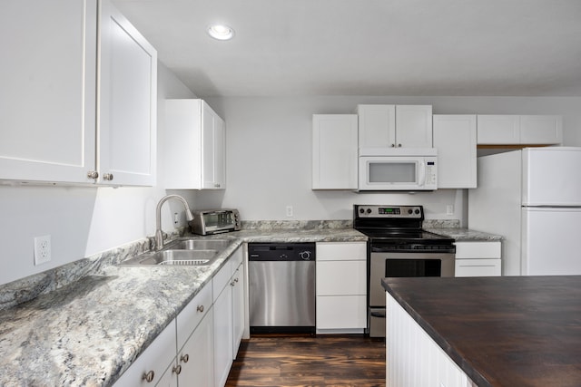 kitchen with dark wood-type flooring, stainless steel appliances, wood counters, sink, and white cabinetry