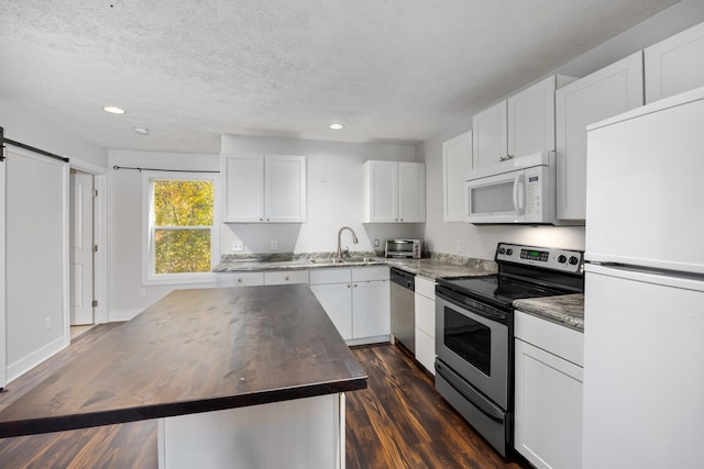 kitchen featuring a kitchen island, dark hardwood / wood-style floors, stainless steel appliances, a barn door, and white cabinetry