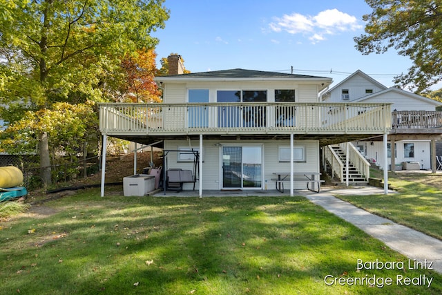 back of house featuring a wooden deck, a patio area, and a lawn