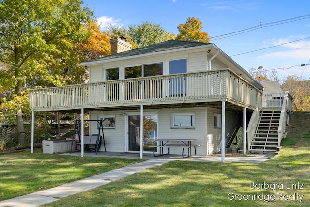 back of house with a wooden deck, a patio, and a lawn