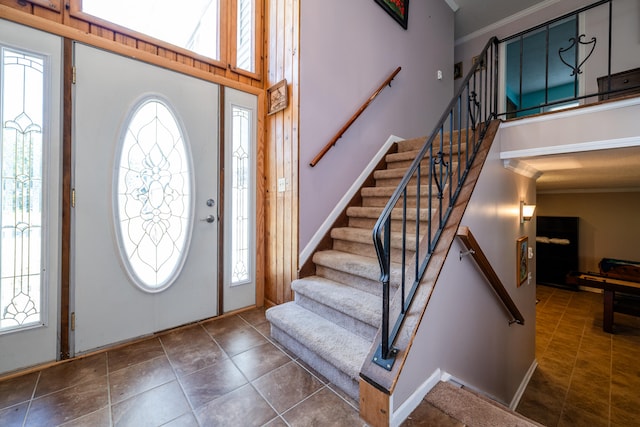 foyer with a towering ceiling, ornamental molding, and a wealth of natural light