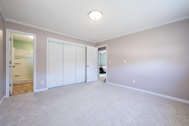 unfurnished bedroom featuring a closet, ensuite bathroom, carpet flooring, and crown molding