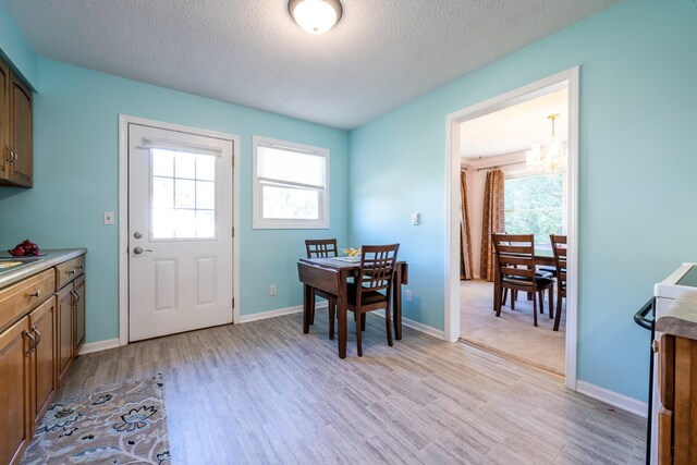 dining room featuring an inviting chandelier, a textured ceiling, and light wood-type flooring