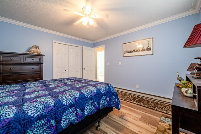 bedroom featuring a baseboard radiator, light wood-type flooring, a closet, ceiling fan, and ornamental molding