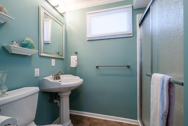 bathroom featuring a shower with door, ornamental molding, and toilet