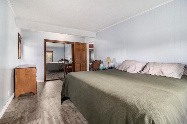 bedroom featuring a closet, wooden walls, hardwood / wood-style floors, and crown molding