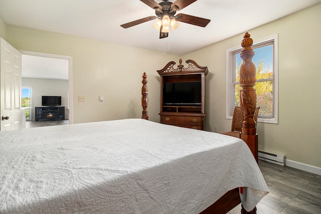 bedroom with a baseboard heating unit, dark wood-type flooring, and ceiling fan