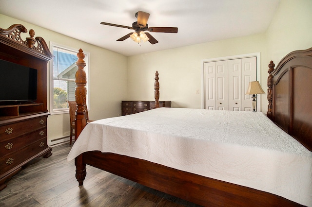 bedroom featuring dark wood-type flooring, ceiling fan, a closet, and a baseboard heating unit