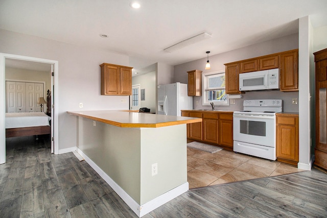 kitchen featuring kitchen peninsula, sink, pendant lighting, light hardwood / wood-style flooring, and white appliances