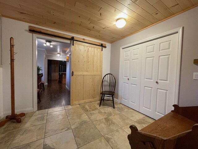 interior space with ornamental molding, hardwood / wood-style floors, a barn door, and wood ceiling