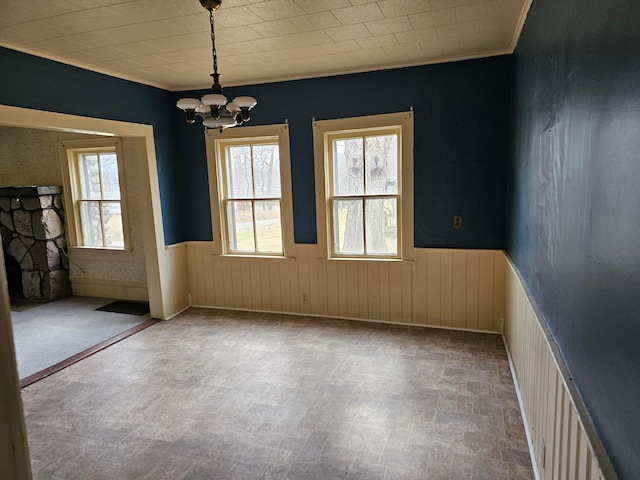 spare room featuring wood walls, ornamental molding, and a notable chandelier