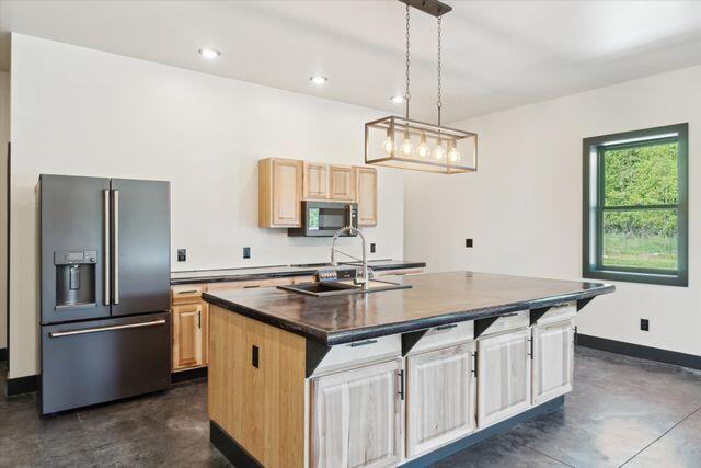 kitchen with an island with sink, sink, stainless steel appliances, and light brown cabinets