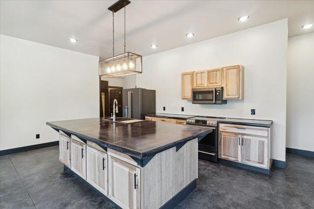 kitchen featuring light brown cabinets, sink, a kitchen island, decorative light fixtures, and appliances with stainless steel finishes