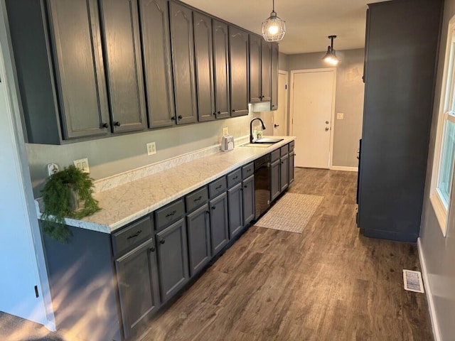 kitchen featuring black dishwasher, dark wood-type flooring, pendant lighting, and sink