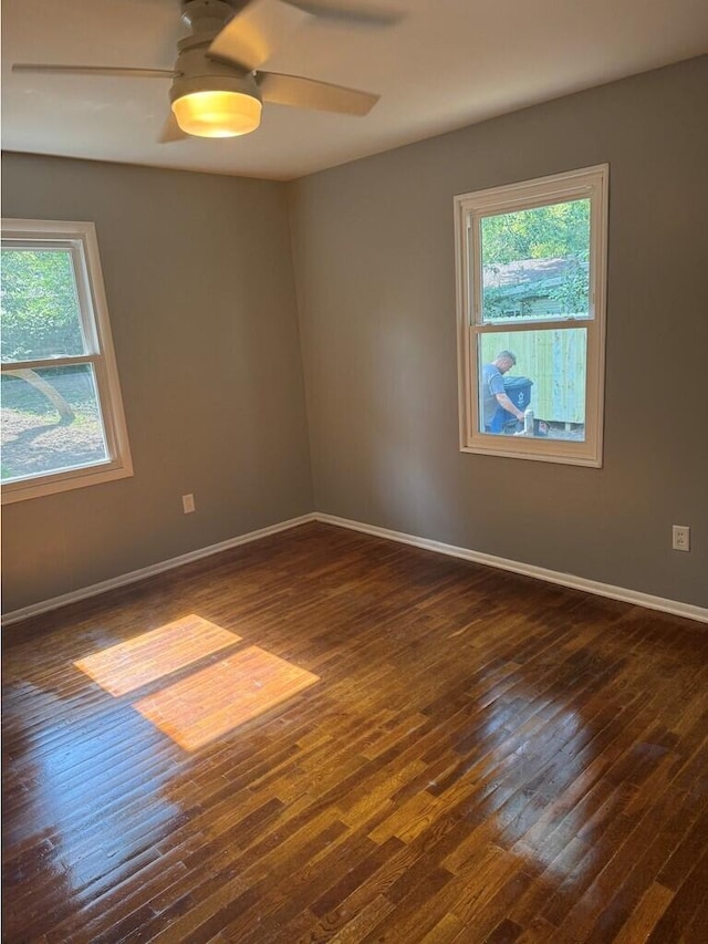 unfurnished room featuring a wealth of natural light, dark wood-type flooring, and ceiling fan