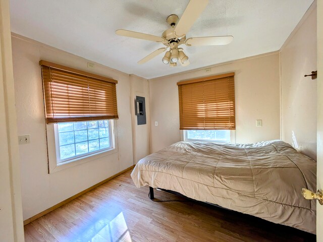 bedroom featuring ceiling fan, multiple windows, and hardwood / wood-style floors