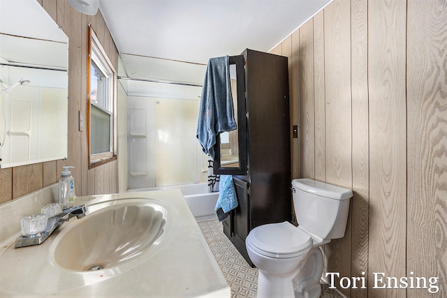 full bathroom featuring  shower combination, sink, wooden walls, and toilet