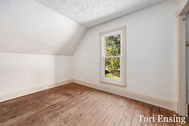 bonus room with dark hardwood / wood-style flooring, vaulted ceiling, a textured ceiling, and plenty of natural light