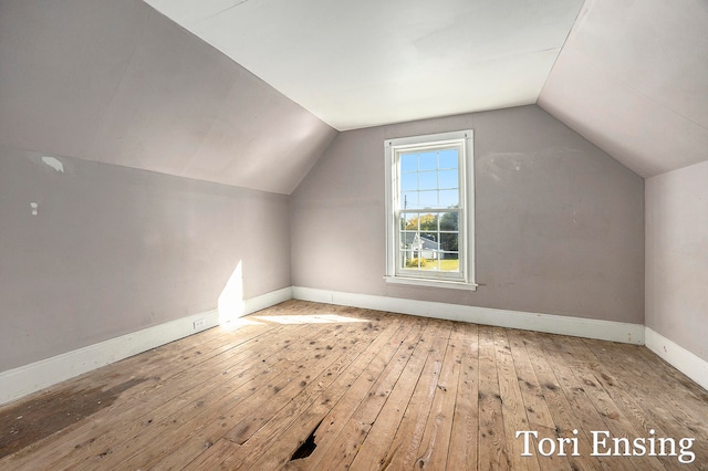 additional living space with hardwood / wood-style flooring and vaulted ceiling