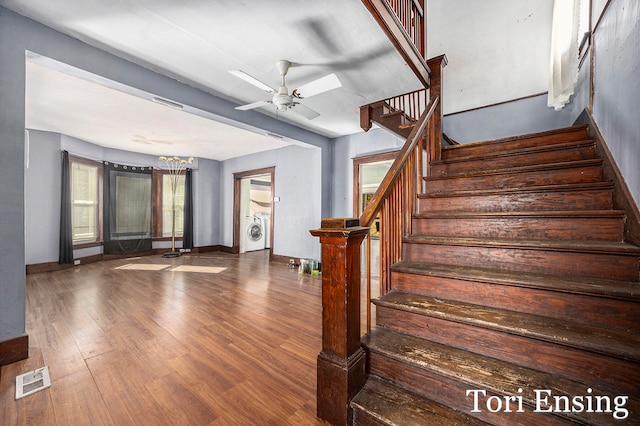 stairway featuring hardwood / wood-style flooring, washer / clothes dryer, and ceiling fan with notable chandelier