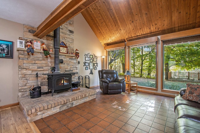 living room featuring a healthy amount of sunlight, tile patterned floors, beamed ceiling, and a wood stove