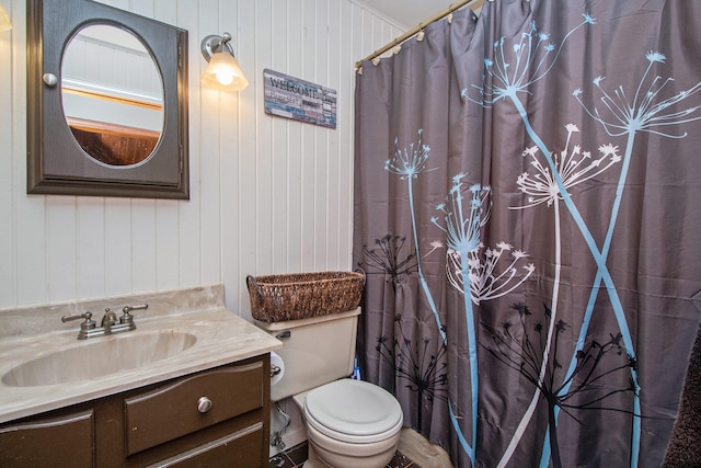 bathroom featuring toilet, curtained shower, vanity, and wooden walls