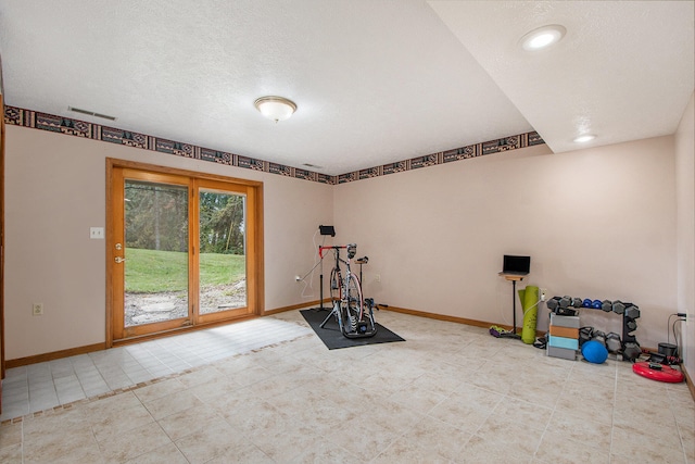 exercise area featuring a textured ceiling and light tile patterned floors