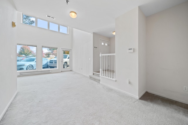 unfurnished living room featuring a towering ceiling and carpet floors