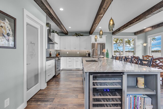 kitchen featuring beverage cooler, appliances with stainless steel finishes, beamed ceiling, pendant lighting, and sink