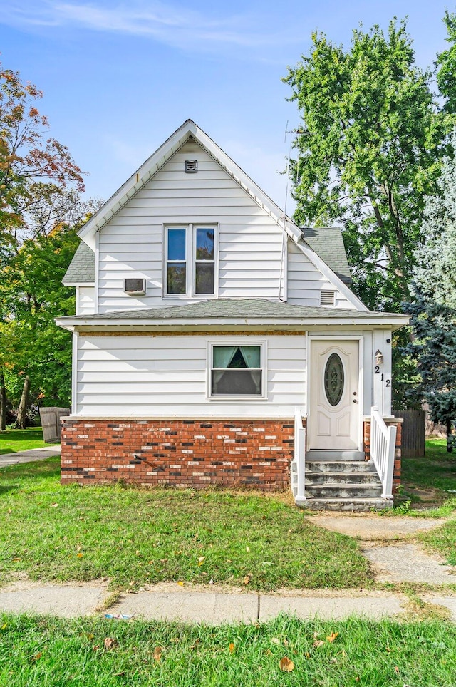 view of front of home with a front yard and a wall mounted air conditioner