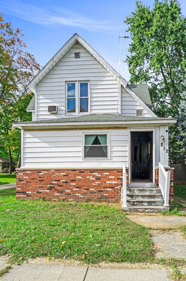 bungalow-style home with an AC wall unit and a front lawn