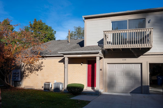 view of front of home featuring central air condition unit, a garage, and a balcony