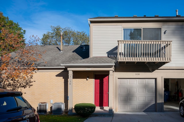 view of front of property with a balcony, a garage, and cooling unit