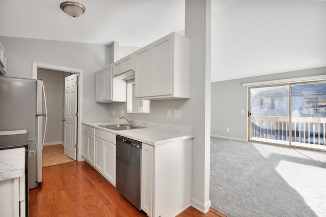 kitchen featuring white cabinetry, appliances with stainless steel finishes, lofted ceiling, and sink