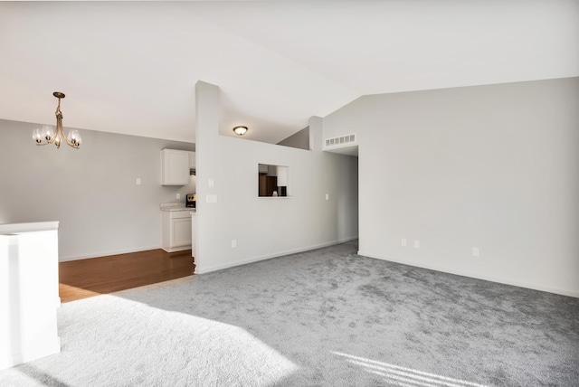 unfurnished living room with vaulted ceiling, carpet flooring, and an inviting chandelier