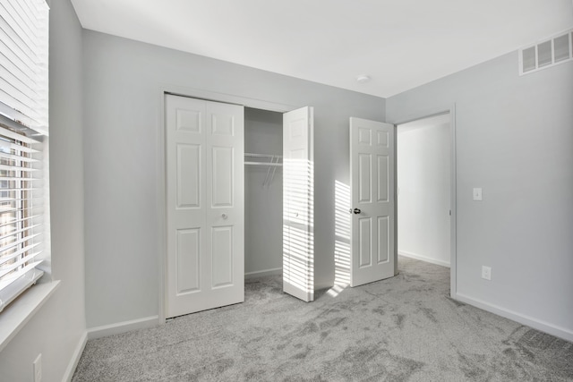 unfurnished bedroom with a closet and light colored carpet