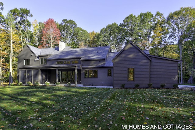 rear view of house with a sunroom and a lawn