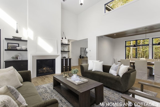 living room featuring high vaulted ceiling and light hardwood / wood-style flooring