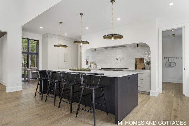 kitchen featuring a large island, light hardwood / wood-style flooring, white cabinets, and hanging light fixtures